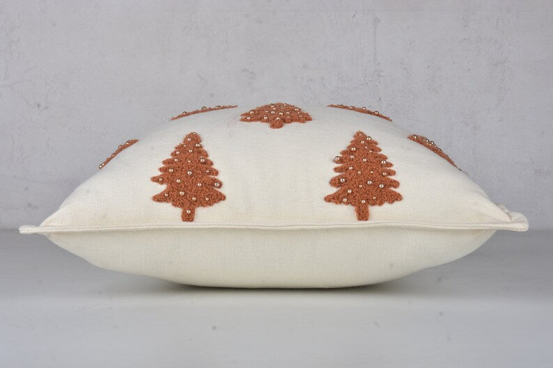 White throw pillow with embroidered brown Christmas trees and silver beads
