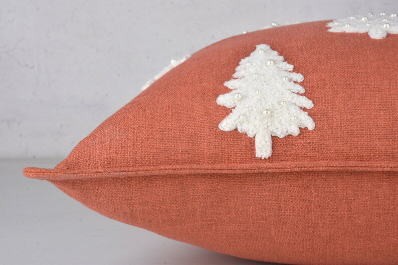 Terracotta throw pillow with two white embroidered Christmas trees and pearl beads
