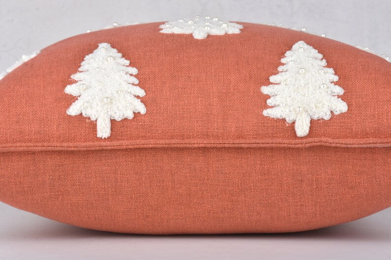 Terracotta throw pillow with three white embroidered Christmas trees and pearl beads