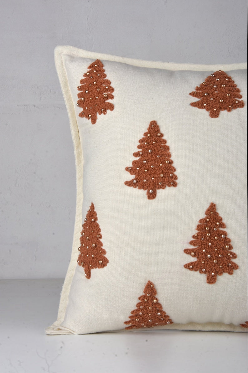 White throw pillow with brown embroidered Christmas trees and pearl-like beads