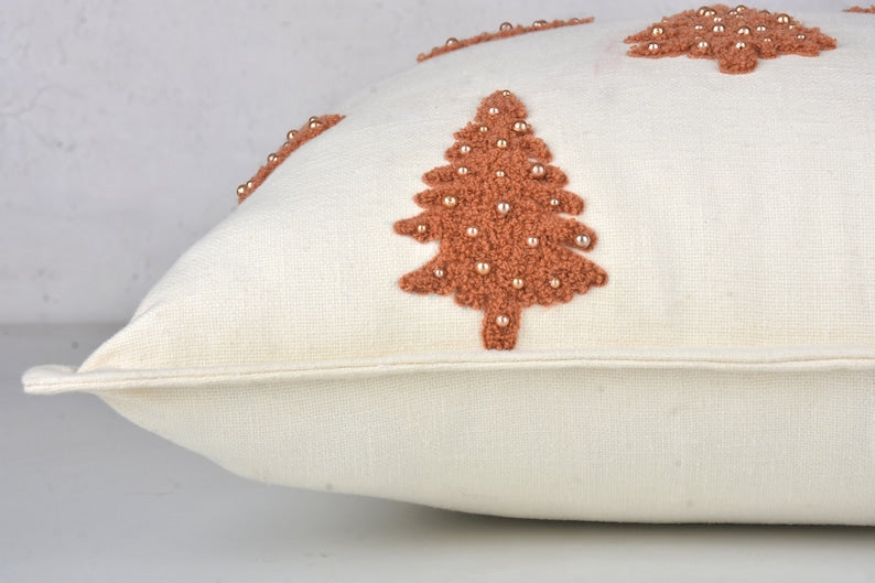 White throw pillow with brown embroidered Christmas tree and gold beads