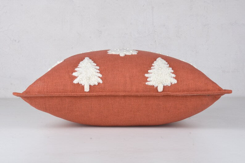 Terracotta throw pillow with three white embroidered Christmas trees decorated with beads