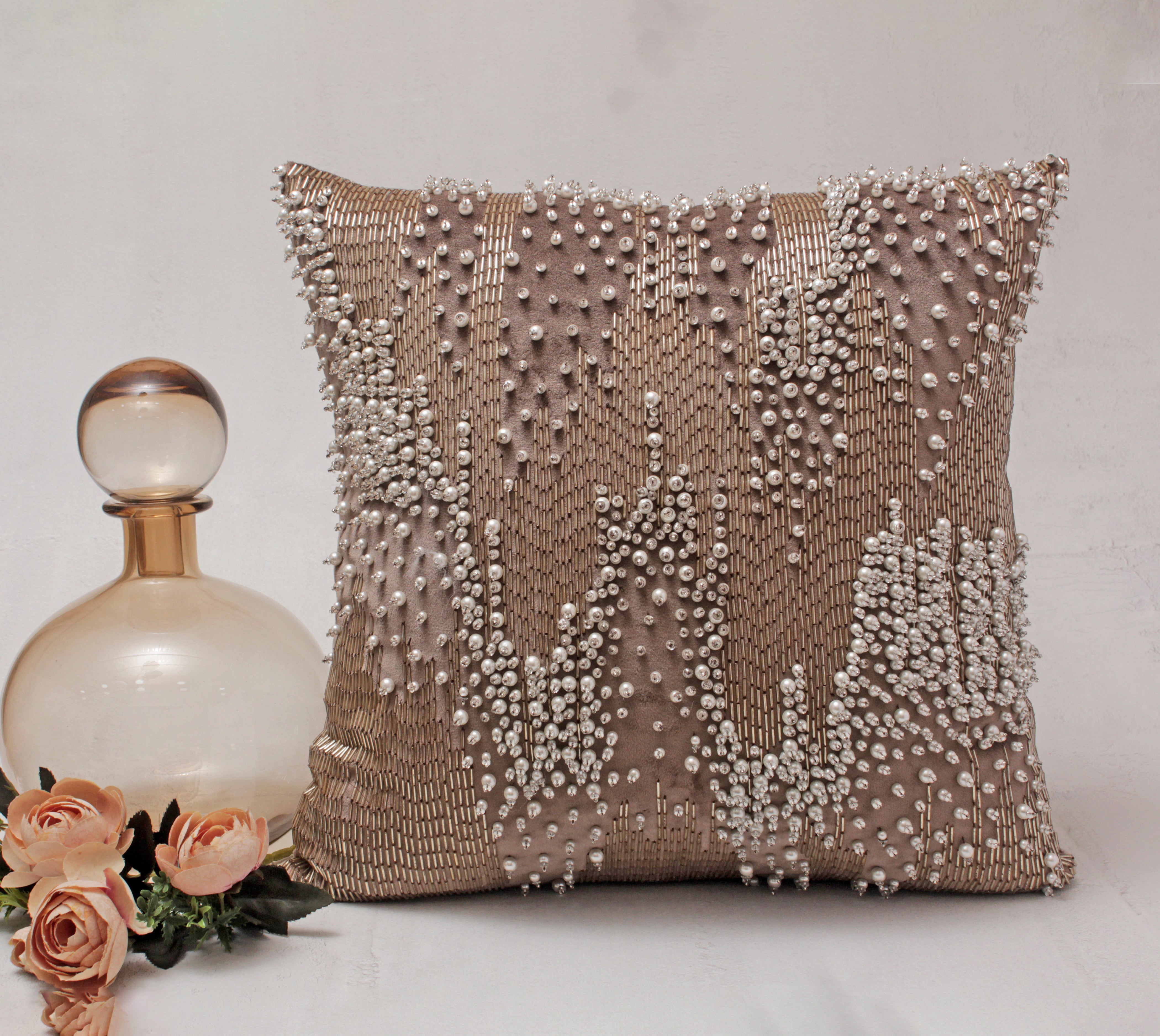The combination of long Glass rods, pearl and crystals in the shades of rosegold and Off-white are used to create a 3 dimensional abstract pattern in an exclusively unique form in the XENIA Cushion Cover.