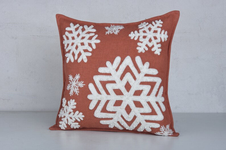 Terracotta throw pillow with embroidered snowflakes and beads