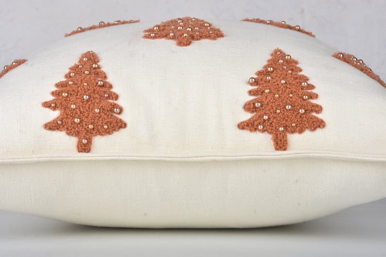 White throw pillow with brown embroidered Christmas trees and pearl-like beads